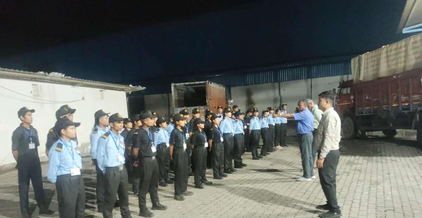 Ex-Army supervisors inspecting a line of DNSMS guards on night parade at a warehouse yard in Guwahati